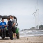 students collecting samples at Woodlawn Beach with wind turbines in the distance. 