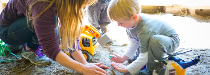 a preschooler digging in the sand on the playground.