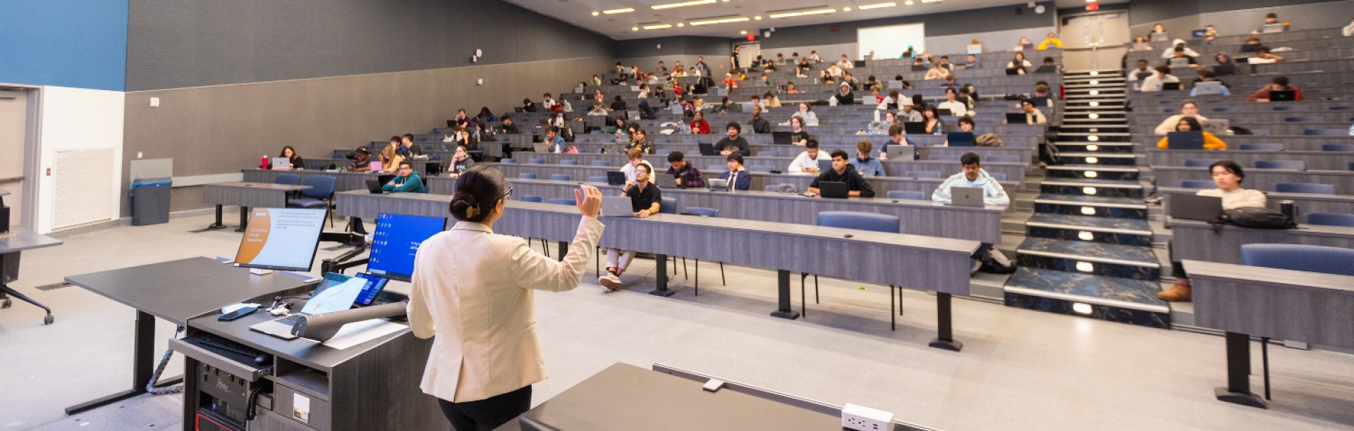 A teacher faces a large lecture hall.