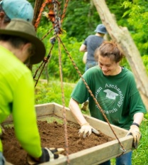 A woman carefully sifting through dirt looking for artifacts.