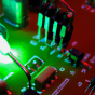 a device lights up while it pokes what looks like a computer circuit board.