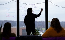 Students with the Glacier Modeling Lab in the Department of Geology, led by Kristin Poinar, meet in their Hochstetter Hall lab space in December 2023. They are mixing fieldwork with the latest developments in AI to map and understand the ever-changing glacial ice in Greenland. PhD candidate Courtney Shafer takes notes on the windows. Photographer: Meredith Forrest Kulwicki. 