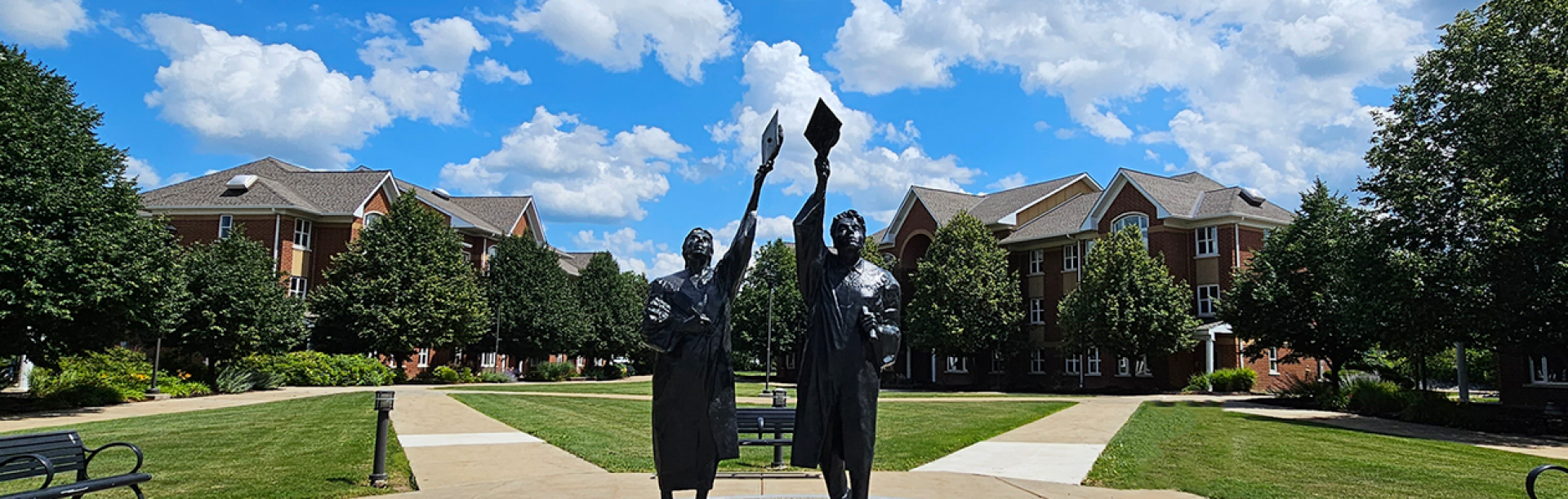 Statue of two graduates tossing up graduation caps in South Lake Village at the University at Buffalo North Campus. 