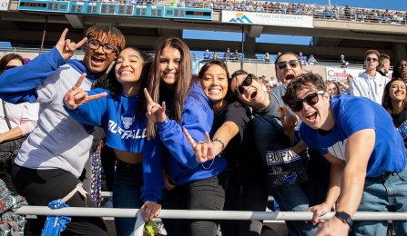 Students cheering in the crowd at a UB football game.