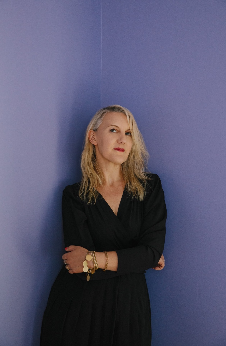 A portrait of Ada Calhoun, a white woman with blonde hair, striking red lips, and a black dress on.