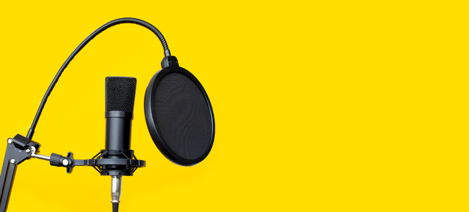 Audio studiio closeup shows microphone on stand. Background color is vivid yellow.