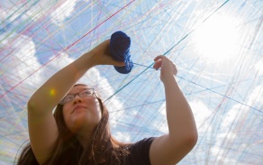 student stringing yarn outside.