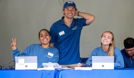 Student workers smiling at the move in check in tent.