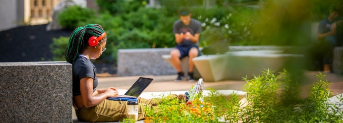 Student working on a computer at Grace Plaza outside Bell and Bonner Halls on North Campus.