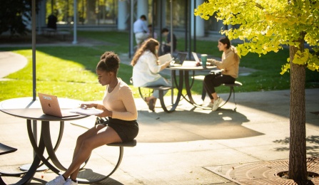 A student poses as it studying outside of Greiner Hall.