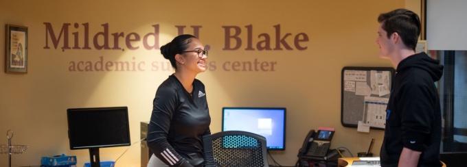 Students talking at the front desk of the Mildred H. Blake academic success center.