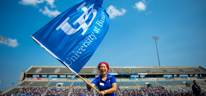 Student waving the UB flag at the football stadium.