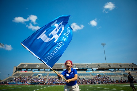 Orientation leader waving a UB flag in the football stadium.
