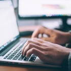 Photo of hands typing on a computer. 