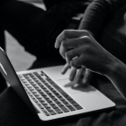 Black and white photo of person typing on a laptop. 