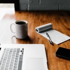 Image of laptop on table with coffee and cell phone. 