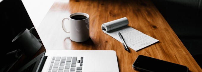 Image of laptop on table with coffee and cell phone. 