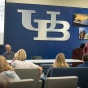 The UB logo is shown on a wall in a classroom. 