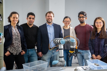 UB professor working on a robotic arm with Computer Science and Engineering students in a Davis Hall lab.
