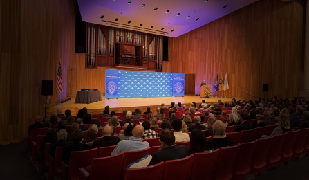 President Tripathi speaking at lectern on Slee Hall stage with UB and Celebration of Academic Excellence backdrop. 