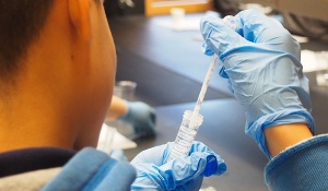 Students swabbed their cheeks, then extracted the DNA from the cheek cells. Close-up photo of a student using a pipette to fill his vile.