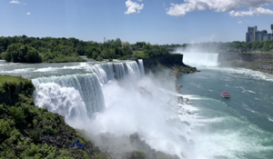 Water flows over Niagara Falls on a sunny day.