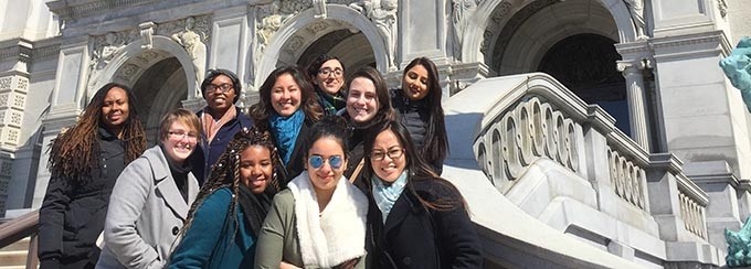 A group of people standing next to large steps, in the winter.