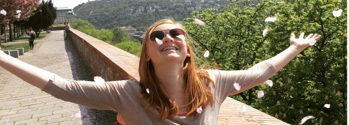 Student with Arms Outstretched and Flower Petals Falling Down in Hungary - Taken by Hannah Anderson.