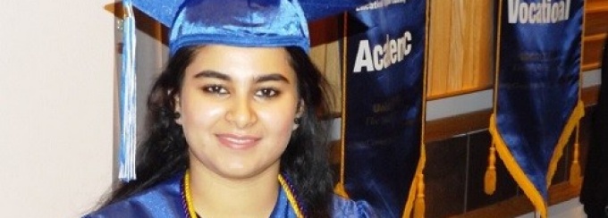 Person in cap and gown looking at camera.