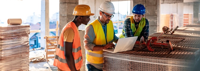 Construction workers discussing by a computer. 