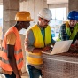 Construction workers discussing by a computer. 