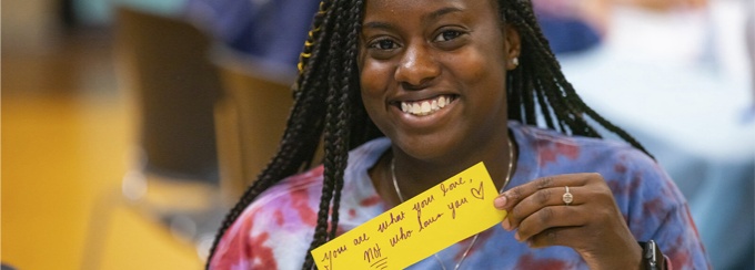 Student showing a note that says you are what you love, not who loves you.