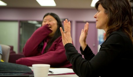 Faculty talking and laughing at a meeting. 