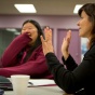 Faculty talking and laughing at a meeting. 