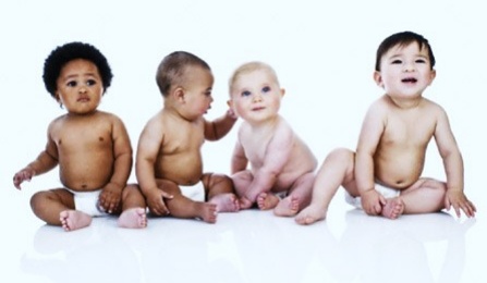 Four babies sitting on the floor.
