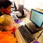 Faculty member helping a student at a computer. 