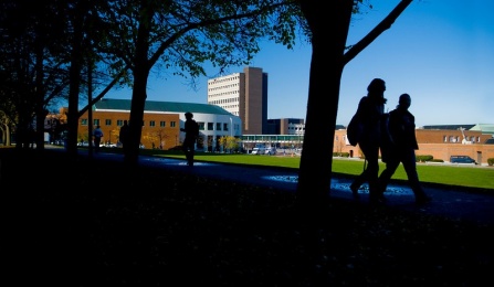 People in silhouette walking outside on the North Campus. 