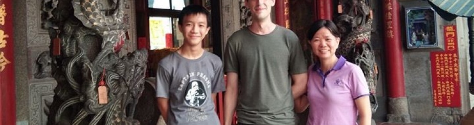 Conor McMahon standing in front of a building with his host family in Taiwan.
