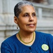 Barbara Smith, woman with short grey hair and gold earings, posed smiling away from camera. 