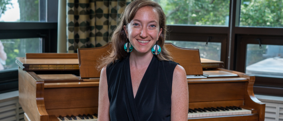 Woman sitting on a piano bench, smiling at the camera. 