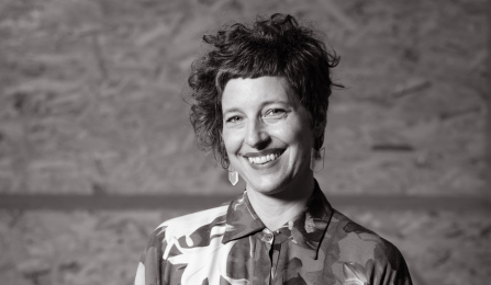 Black and white photo of a person with short hair, smiling into the camera.