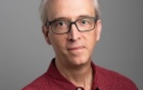 Man smiling at the camera, wearing a red shirt.