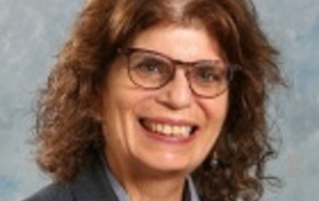 Woman with dark hair and glasses, smiling at the camera.