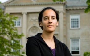 Woman standing outdoors, arms crossed.
