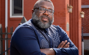 Man with arms crossed, looking into the camera.