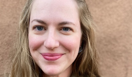 A woman with dark blonde hair, wearing a green shirt, smiling at the camera.