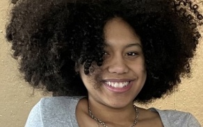 Person with curly, dark hair, smiling at the camera.