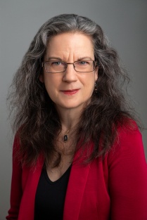 Photo shows woman wearing a red blazer looking at the camera.