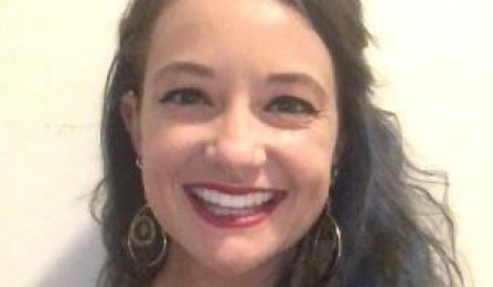 Photo shows a woman with dark hair smiling at the camera. 