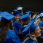 students sitting and laughing while wearing graduation caps and gowns. 